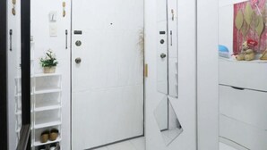 Une porte blanche avec un trou de serrure, une petite plante et un porte-chaussures contenant des chaussures.