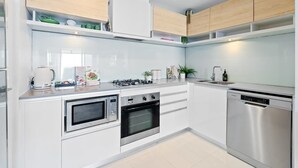 Una cocina moderna con armarios blancos, electrodomésticos de acero inoxidable y horno empotrado.