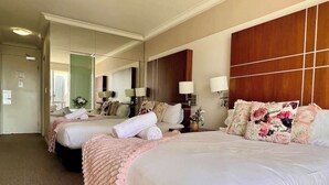Una camera d'albergo con due letti, un grande specchio e una testiera in legno.