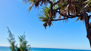 Una spiaggia con cielo sereno, onde dell'oceano e alcune persone che passeggiano.