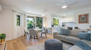Ein modernes Wohnzimmer mit Sofa, Esstisch, Stühlen, einer Küchenzeile und einem Balkon mit Blick.