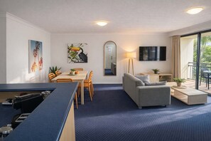 A hotel room with a dining area, a sofa, a TV, and a balcony with a view. - 2BR Turtle Beach Mermaid Beach Aircon (Mermaid Beach)