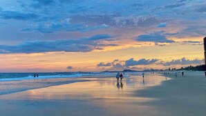 Ein Strand mit Spaziergängern, einem Sonnenuntergang und einem klaren Himmel.