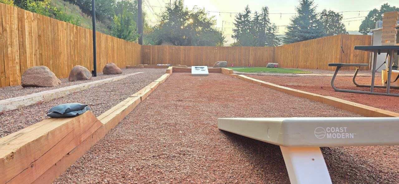 An outdoor area with a wooden fence, a gravel path, and a picnic table.