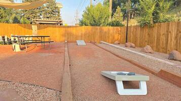 An outdoor area with a wooden fence, a table, and a chessboard.