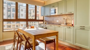 A kitchen with a wooden table, chairs, a microwave, and cabinets. - Refuge in Funchal II, a Home in Madeira (Funchal)