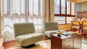 A modern living room with two armchairs, a coffee table, and a view of the city through large windows. - Refuge in Funchal II, a Home in Madeira (Funchal)