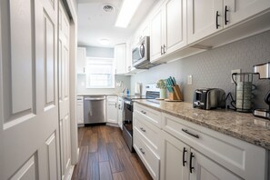 A modern kitchen with white cabinetry, a microwave, a toaster, and a coffee maker. - Wonderful 2-bedroom townhome close to beach +Pool (Myrtle Beach)