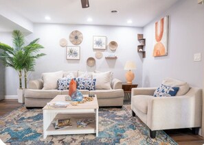 A living room with a sofa, armchair, coffee table, and decorative items on the walls. - Wonderful 2-bedroom townhome close to beach +Pool (Myrtle Beach)