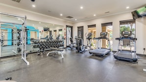 Ein Fitnessstudio mit Laufbändern, Crosstrainern und Gewichten.