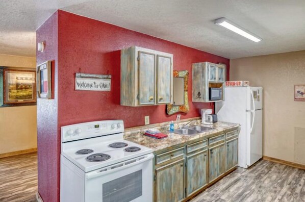 A kitchen with a white stove, a sink, and cabinets. - Riverfront Cabins  and  Vacation Homes (Rio Frio)