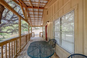 A covered porch with a table and chairs, wooden railings, and large windows. - Riverfront Cabins  and  Vacation Homes (Rio Frio)
