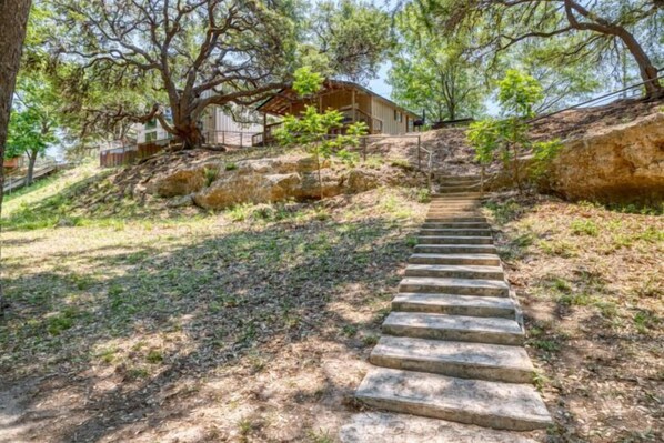 Una escalera de piedra que sube con una casa al fondo.