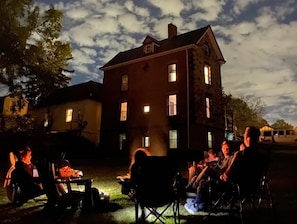 A group of people seated outdoors at night, with a building in the background. - Giant stone house walkable to everything vibrant Westwood has to offer in Cincy (Cincinnati)