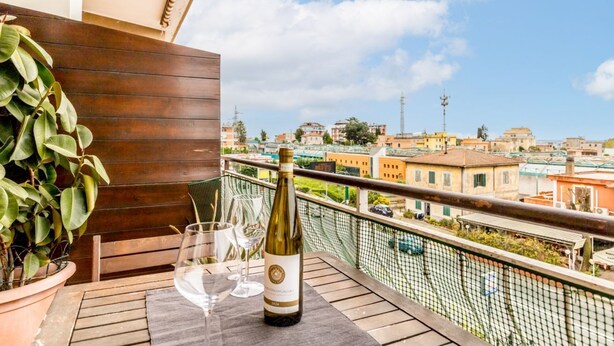 A balcony with a bottle of wine, glasses, and a potted plant. - La casa di Faffo [Trionfale] (Rome)