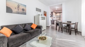 A modern living room with a grey sofa, orange cushions, a glass coffee table, and a dining area with a wooden table and chairs. - La casa di Faffo [Trionfale] (Rome)