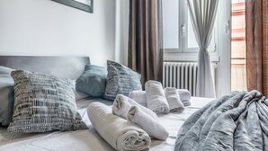 A hotel room with a bed, pillows, towels, a window with curtains, and a radiator. - La casa di Faffo [Trionfale] (Rome)