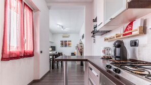 A modern kitchen with a gas stove, wooden cabinets, and a dining area with a table and chairs. - La casa di Faffo [Trionfale] (Rome)