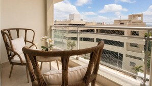 A balcony with wicker furniture, a small table, and a potted plant. - Majestuoso Apartamento 2 habitaciones  (Boca Chica)