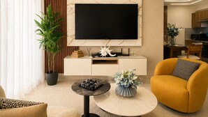 A modern living room with a flat-screen TV, a sofa, a coffee table, and a potted plant. - Majestuoso Apartamento 2 habitaciones  (Boca Chica)