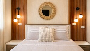 A bedroom with a bed, two wall-mounted lights, a round mirror, and a wooden panel wall. - Majestuoso Apartamento 2 habitaciones  (Boca Chica)