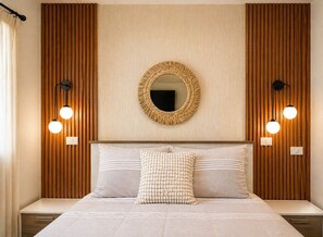 Ein Schlafzimmer mit einem Bett, zwei Wandleuchten, einem runden Spiegel und einer Wandverkleidung aus Holz.