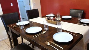 Une table à manger dressée avec des assiettes, des couverts et des verres, agrémentée d’un centre de table décoratif.