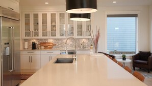 A modern kitchen with a large island, stainless steel appliances, and a dining area with a view. - Bright 3BR Langley Home | Ensuite + Office + Parking (Langley Township)