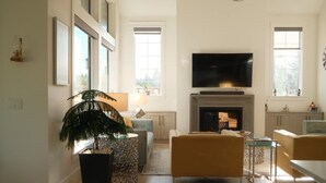 A spacious living room with a fireplace, a television, and a large window. - Bright 3BR Langley Home | Ensuite + Office + Parking (Langley Township)