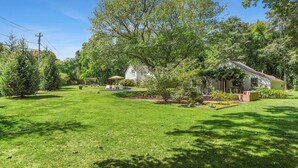 A residential property with a well-maintained lawn, a small patio area, and a house surrounded by trees. - Charming property with 2 small cottages with 1-bedroom each in lovely Water Mill (Water Mill)