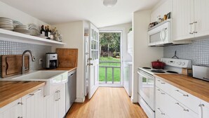 A kitchen with white cabinets, a wooden countertop, a built-in microwave, and a view to the outside. - Charming property with 2 small cottages with 1-bedroom each in lovely Water Mill (Water Mill)