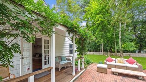 A covered porch with wicker furniture, a wooden bench, and a brick patio. - Charming property with 2 small cottages with 1-bedroom each in lovely Water Mill (Water Mill)