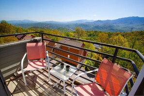 A balcony with a table, two chairs, and a view of a mountainous landscape. - Ski View LookOut: EPIC VIEWS! Community Amenities! (Gatlinburg)