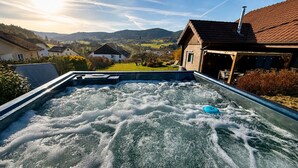 Een bubbelbad met uitzicht op een landelijk landschap, inclusief huizen en heuvels.