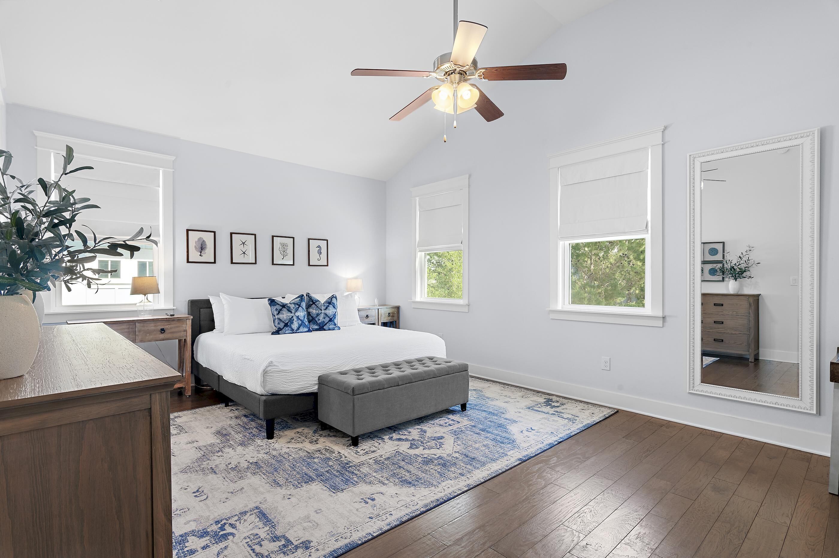 A bedroom with a bed, bedside tables, a ceiling fan, a large mirror, and a window.