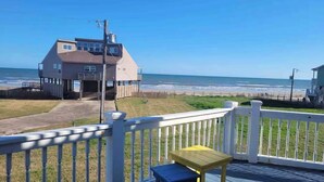Een huis aan de kust met een terras, een kleine tafel en uitzicht op zee.