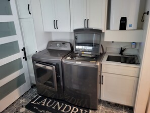 A compact laundry area with a washing machine, dryer, and a small sink.