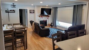 Una sala de estar moderna con chimenea, televisor y comedor con mesa y sillas.