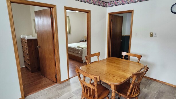 A room with a wooden dining table, chairs, a dresser, and a bed. - Crocker Cabins Unit 1 offers a self‑contained efficiency unit in Gros Morne. (Trout River)