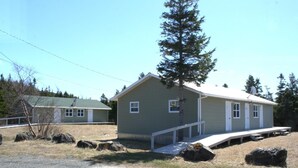 A single-story building with a porch, a small window, and a door. - Crocker Cabins Unit 1 offers a self‑contained efficiency unit in Gros Morne. (Trout River)