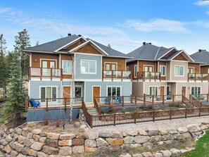 A multi-story residential building with a stone retaining wall, wooden deck, and outdoor seating.