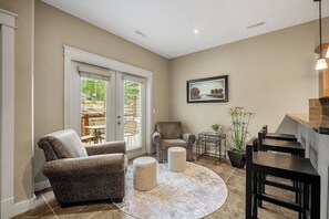 A living room with a sofa, ottoman, and a dining area with a table and chairs.