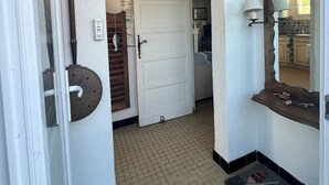 A hallway with a white door, a tiled floor, a wooden door frame, and a mirror with a shelf. - Family house at the foot of the dune 3 min between beach and market🤩🚲⛱️ (La Couarde-sur-Mer)