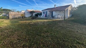 A house with a patio area, a small garden, and a clear blue sky. - Family house at the foot of the dune 3 min between beach and market🤩🚲⛱️ (La Couarde-sur-Mer)