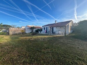 Ein Haus mit Terrasse, kleinem Garten und blauem Himmel.