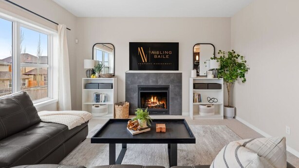 A modern living room with a fireplace, a black coffee table, a sofa, and a bookshelf. - Merlot | AC | Crib | Fenced Yard | Pets Ok (Calgary)