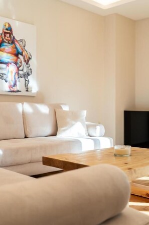 A modern living room with a sofa, a coffee table, and a painting on the wall. - MZ Kolonaki (Athens)