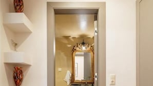 A hallway with a wooden floor, a mirror with a decorative frame, and white shelves with vases. - MZ Kolonaki (Athens)