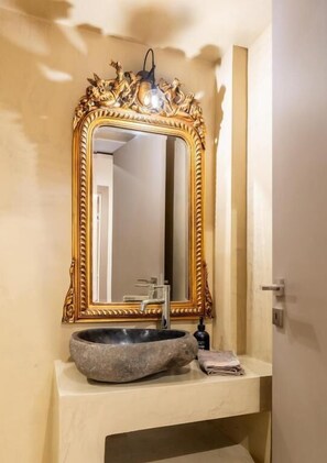 A bathroom with a large ornate mirror, a stone basin, and a towel on the counter. - MZ Kolonaki (Athens)