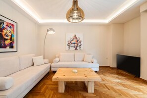 Ein modernes Wohnzimmer mit einer Couch, einem Couchtisch, einem Gemälde, einer Stehlampe und einem Fernseher.